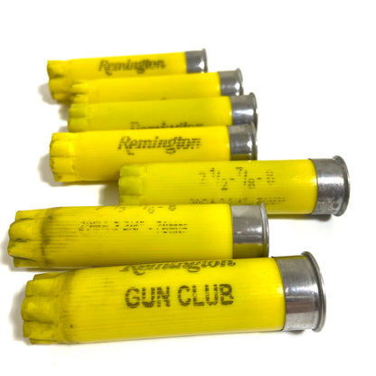7 yellow Remington Gun Club shell casings fanned out showing brand markings