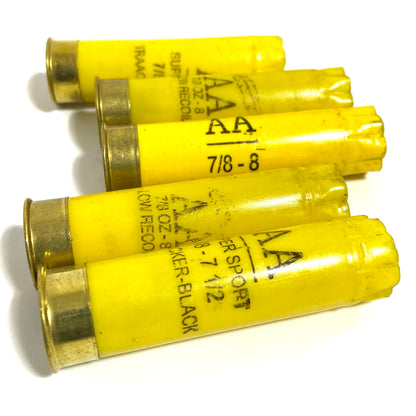 Five empty yellow shotgun shells lie crossed together, showing various Winchester AA text markings.