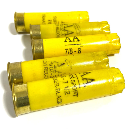 Five empty yellow shotgun shells lie crossed together, showing various Winchester AA text markings.