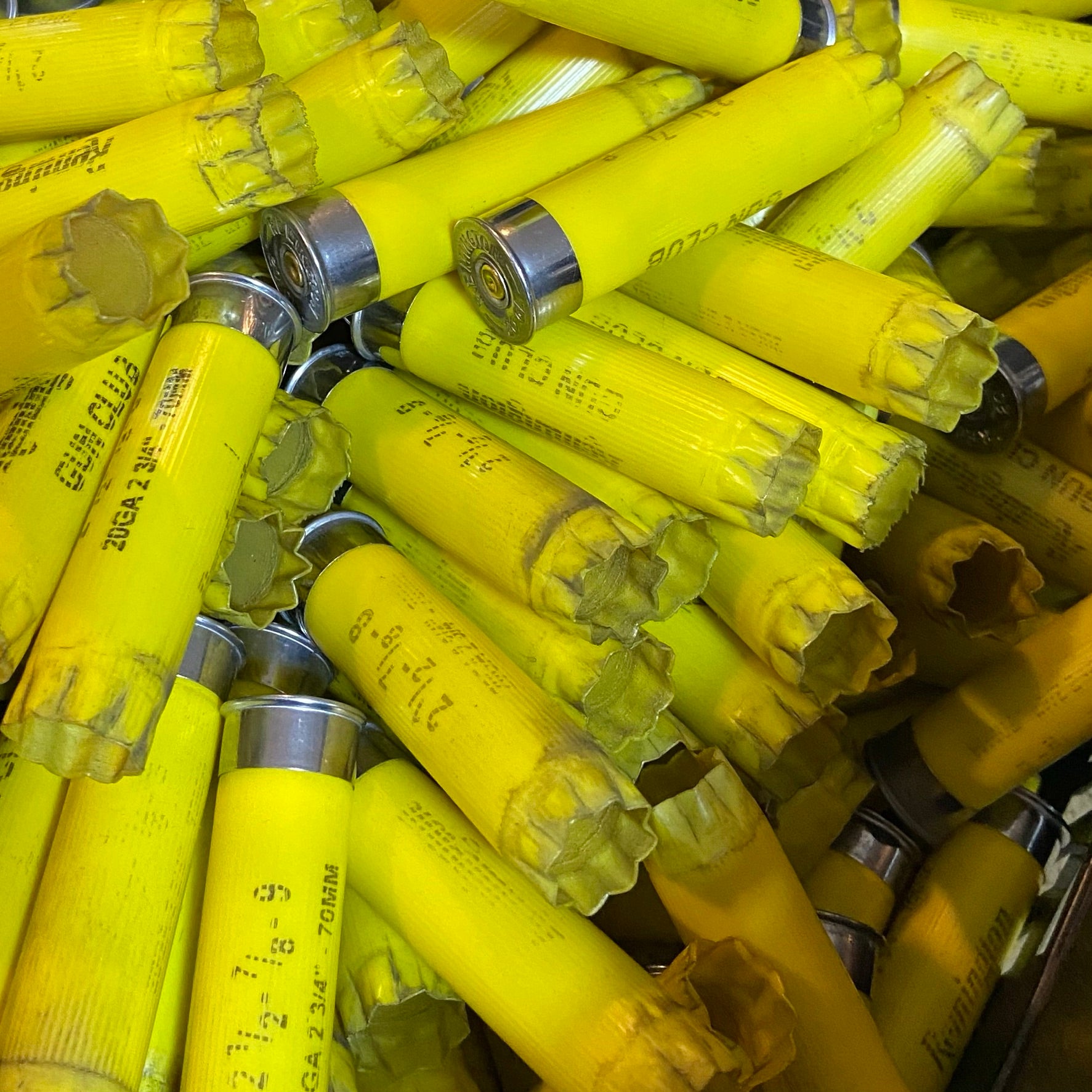 Pile of used yellow casings showing folded crimp ends and some torn openings