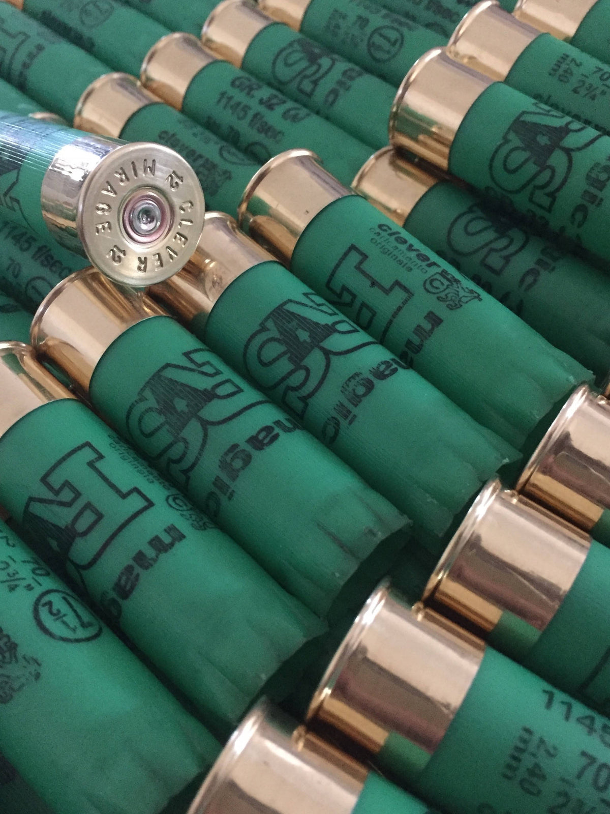 Rows of green shotgun shells with gold bases, one shell tilted showing a silver base embossed "Clever Mirage"